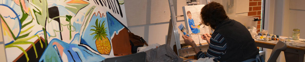 Student sitting at an easel working on a painting