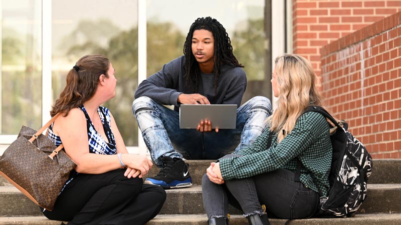 Three students outside on the back patio at KCC