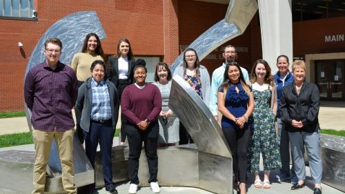 The Criminal Justice Club posing on the metal sculpture in front of the KCC main entrance